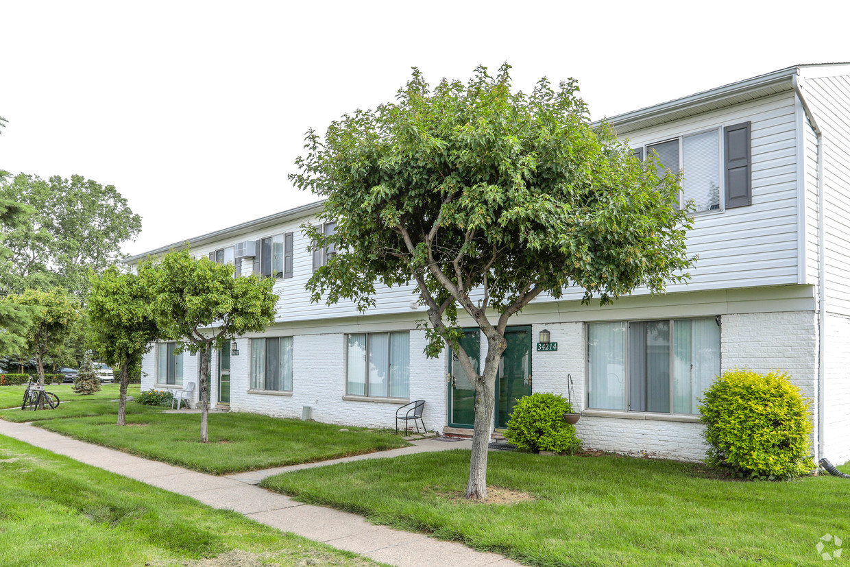 A row of houses with trees in front.