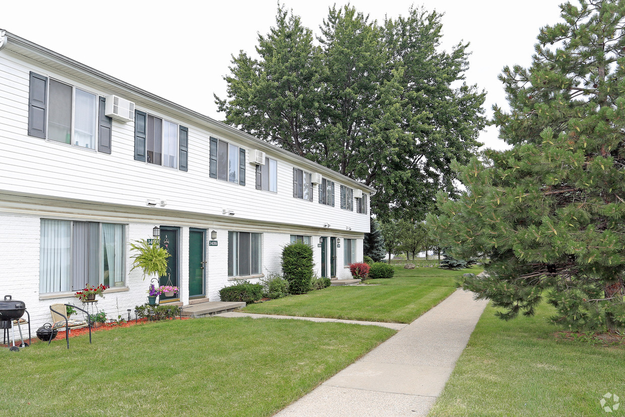 A green lawn with trees and buildings in the background.