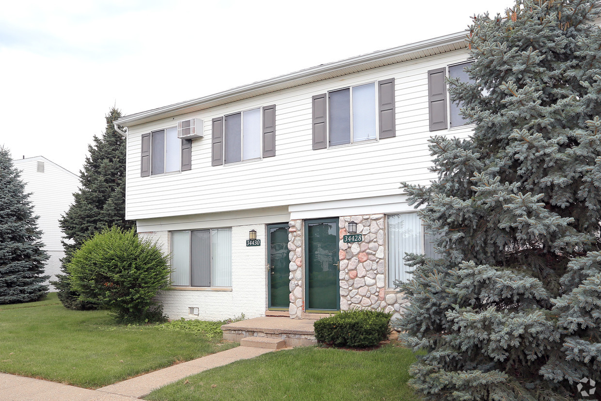 A white two story house with green shutters.